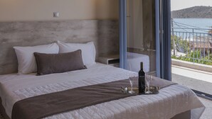 A bedroom with a large bed, a glass door leading to a balcony, and a view of the sea. - Vivari Acta (Nafplio)