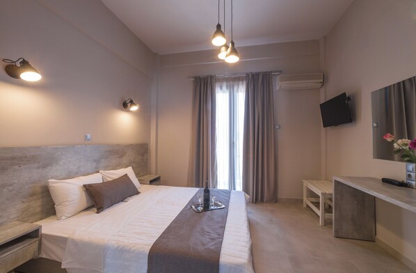 A modern hotel room with a large bed, bedside table, and a desk with a chair. - Vivari Acta (Nafplio)