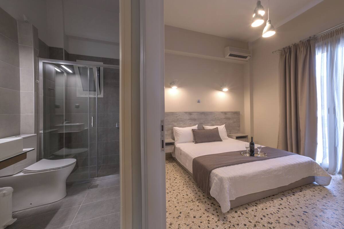 A modern hotel room with a shower, toilet, and bed.