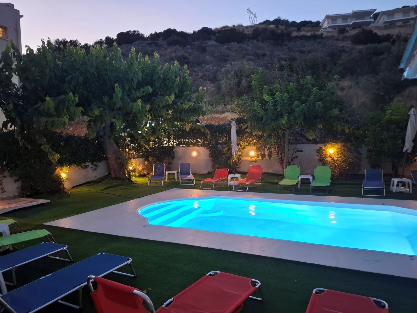Una piscina con sillones de descanso y un césped.