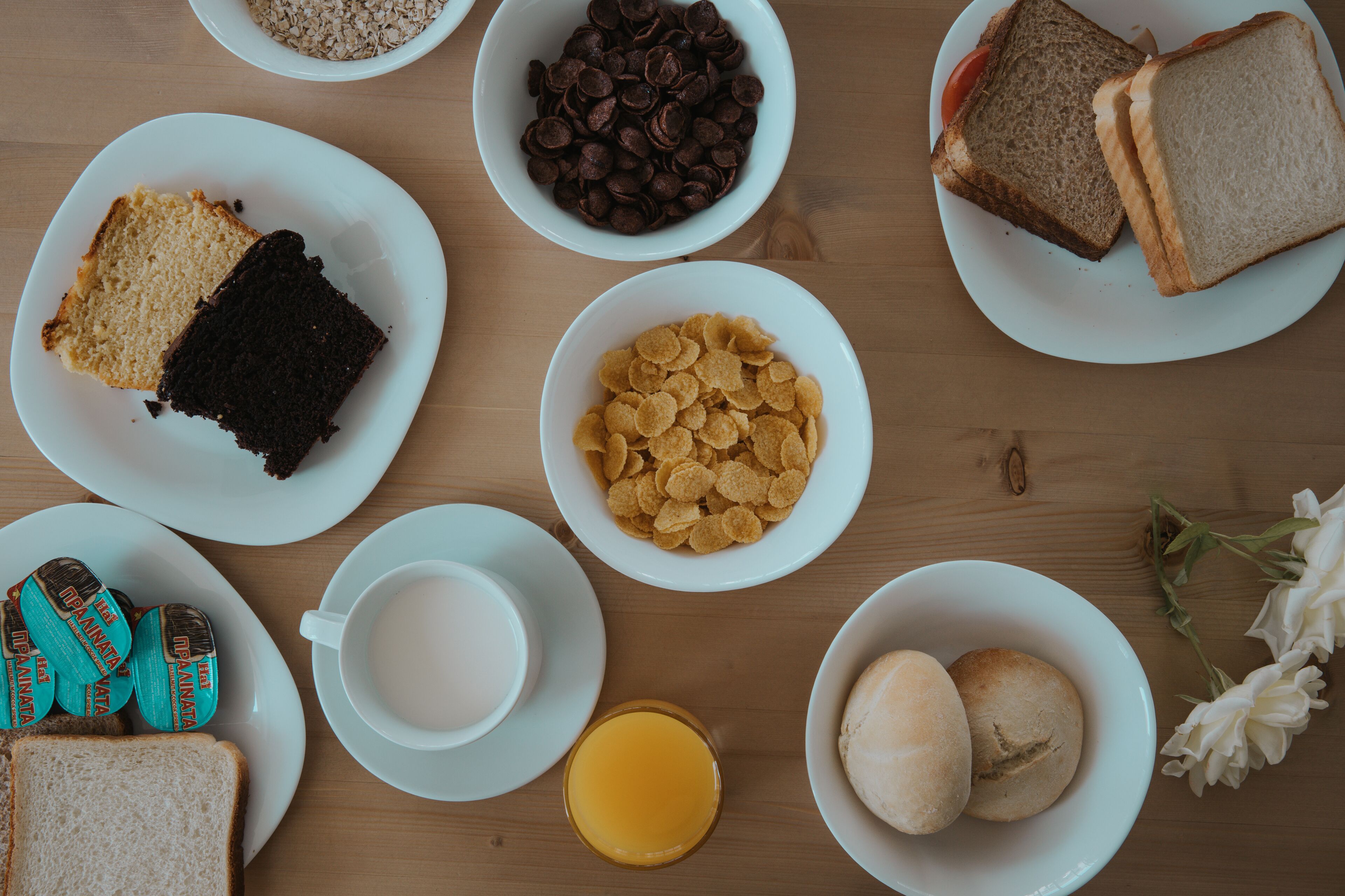A breakfast setting with various food items on plates, including bread, cereal, and a glass of orange juice.