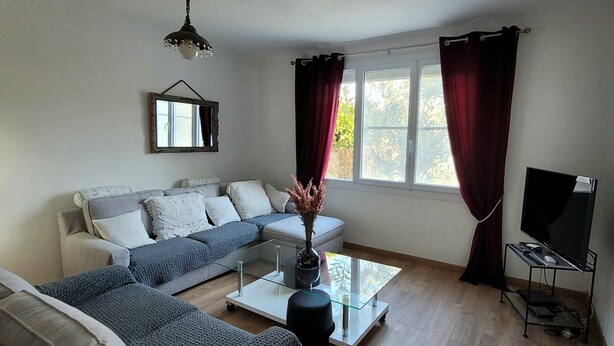 Een woonkamer met een bank, een salontafel, een tv-meubel en een raam met gordijnen.