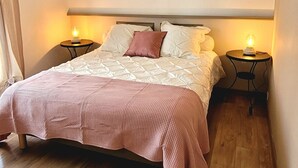 Een slaapkamer met een groot bed, twee nachtkastjes, een kroonluchter en een lijst met een afbeelding aan de muur.