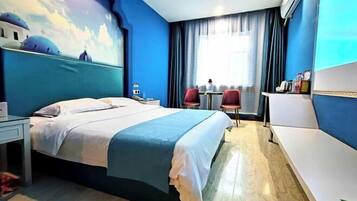 Habitación de hotel con cama, escritorio, silla, una mesita y ventana con cortinas.
