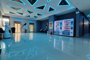 Un vestíbulo moderno con un robot, máquinas expendedoras y un piso limpio y reflectante.