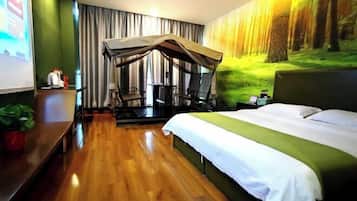A hotel room with a bed, a desk, a chair, a small table, a plant, and a canopy bed.