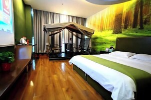 Habitación de hotel con cama, escritorio, silla, pequeña mesa, planta y dosel.