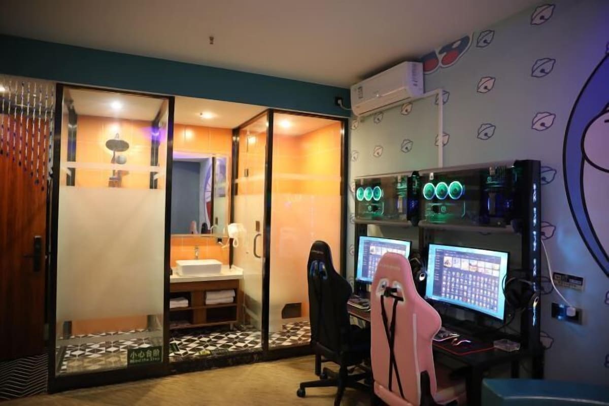 Ein Zimmer mit Gaming-Einrichtung, darunter zwei Monitore, ein Gaming-Stuhl und ein Schreibtisch. An der Wand befindet sich ein großer Spiegel und ein Fenster mit Jalousien.