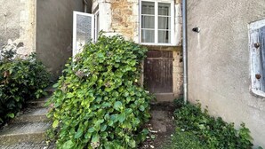 A stone building with a wooden door and a window. - Nid douillet - Centre historique (Buxy)