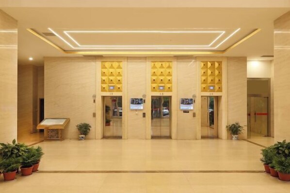 A hotel lobby with a modern design, featuring a reception desk, elevators, and potted plants. - Boxiyueli Hotel (Wuxi Yuantouzhu Scenic Area) (Wuxi)