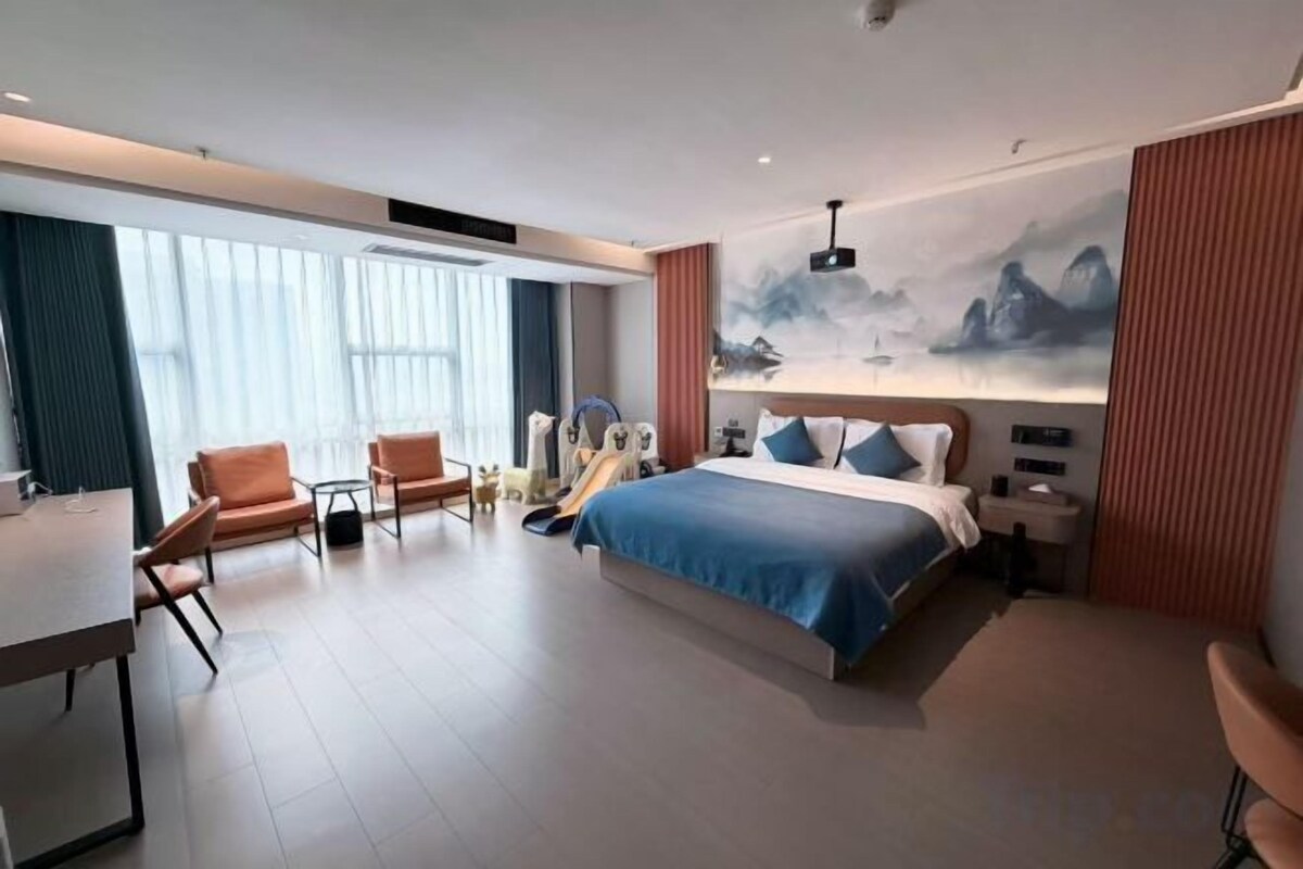 A modern hotel room with a large bed, a desk, and a chair.