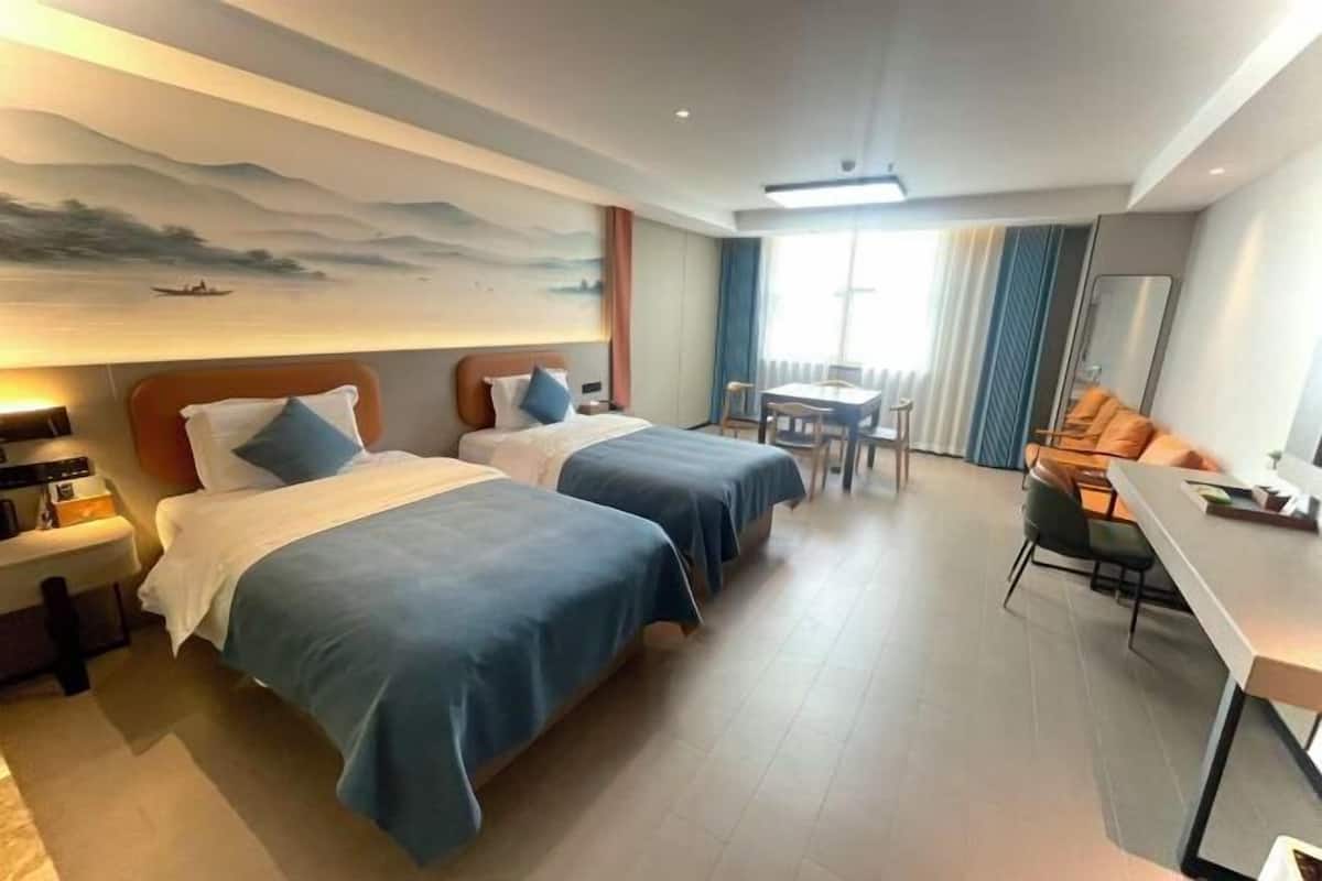 A hotel room with two beds, a desk, and a dining area.