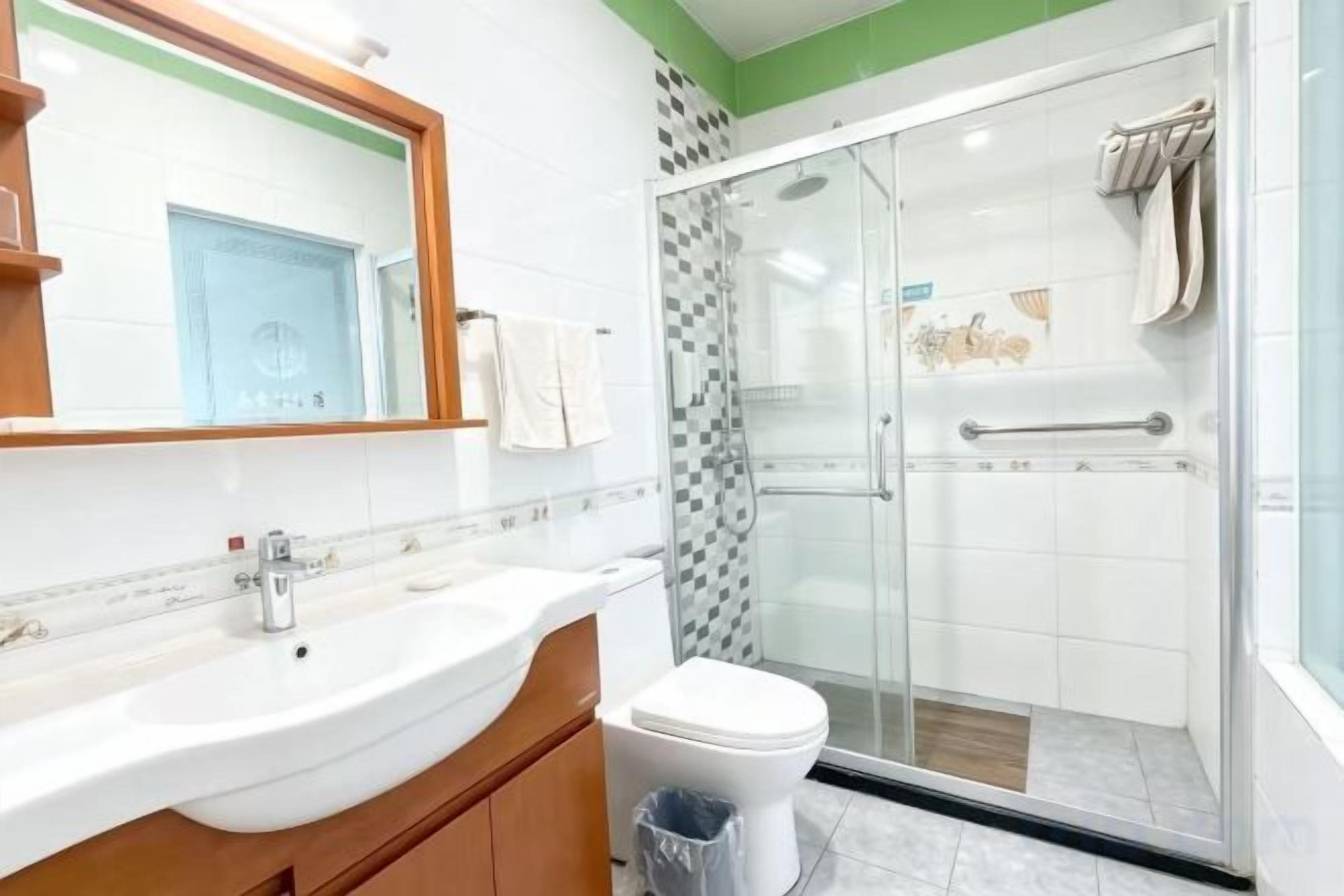 Une salle de bain avec un lavabo blanc, un miroir et une douche fermée par des parois de verre.