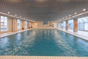 An indoor swimming pool with clear water, tiled walls, and a ceiling with a grid pattern. - Gao Qing Ying Bin Hotel(Laocheng Craftsmen Museum) (Gaoqing)