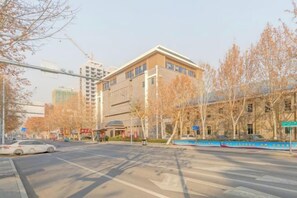A street view with a building that has multiple floors and a flat roof. There are trees with no leaves, suggesting it might be autumn or winter. - Gao Qing Ying Bin Hotel（Laocheng Craftsmen Museum） (Gaoqing)