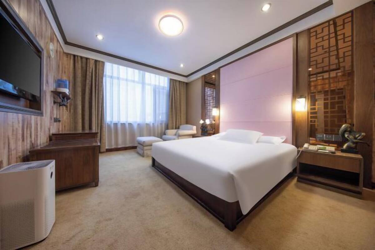 Una habitación de hotel con una cama grande, televisión, escritorio y silla.