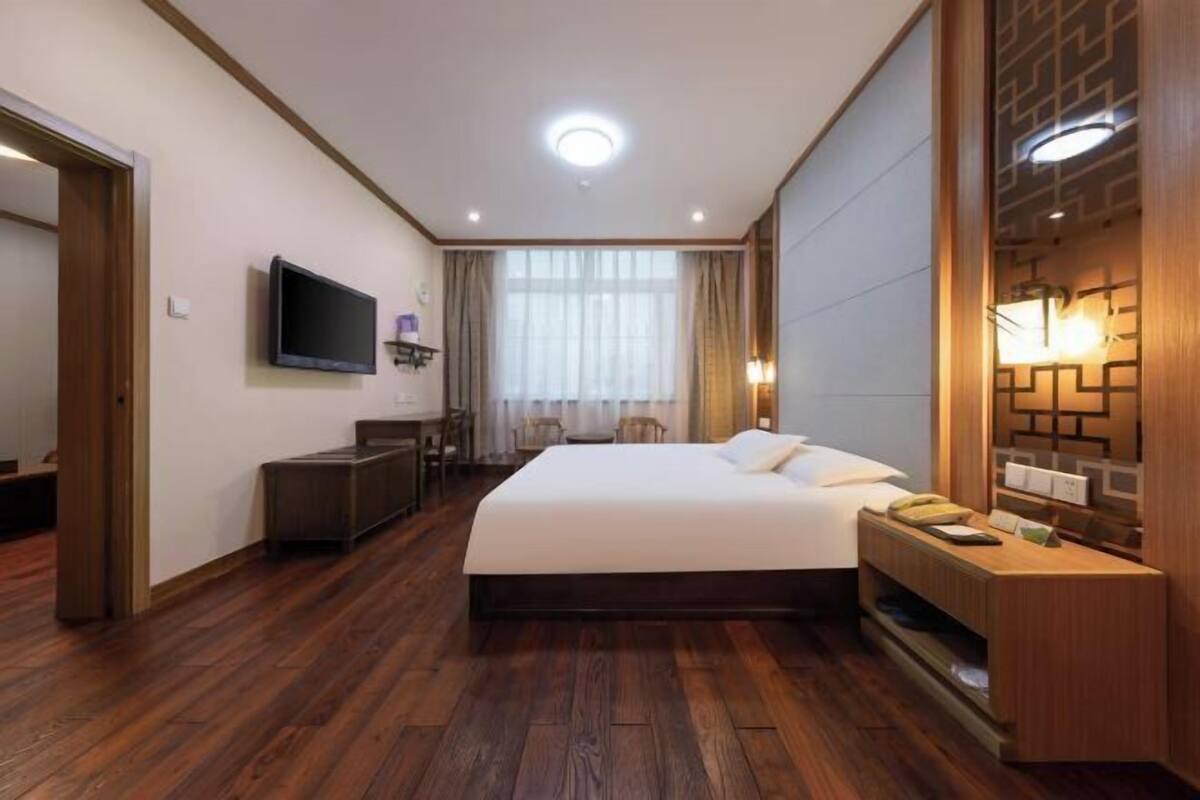 Una habitación de hotel con una cama grande, un escritorio, un televisor y una recepción.