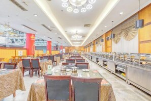 A spacious cafeteria with multiple tables and chairs, a buffet line, and a high ceiling with circular light fixtures. - Gao Qing Ying Bin Hotel（Laocheng Craftsmen Museum） (Gaoqing)