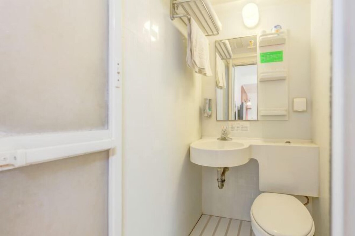 Ein kleines, kompaktes Badezimmer mit Waschbecken, Spiegel und Toilette in Weiß.