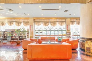 A lobby with a seating area, bookshelves, and a coffee machine. - Gao Qing Ying Bin Hotel（Laocheng Craftsmen Museum） (Gaoqing)