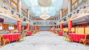 A spacious banquet hall with round tables and chairs, a chandelier, and a high ceiling. - Gao Qing Ying Bin Hotel（Laocheng Craftsmen Museum） (Gaoqing)