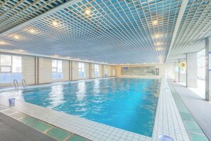 An indoor swimming pool with a tiled floor, clear ceiling, and windows along one side. - Gao Qing Ying Bin Hotel（Laocheng Craftsmen Museum） (Gaoqing)