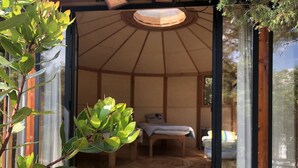 A cozy, open-plan room with a wooden floor, a bed, and a small table.