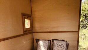 A wooden bed with heart-patterned bedding in a room with wooden walls and a small window.