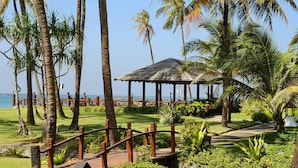 Ein Gazebo mit Ziegeldach, umgeben von Palmen und einer Holzterrasse.