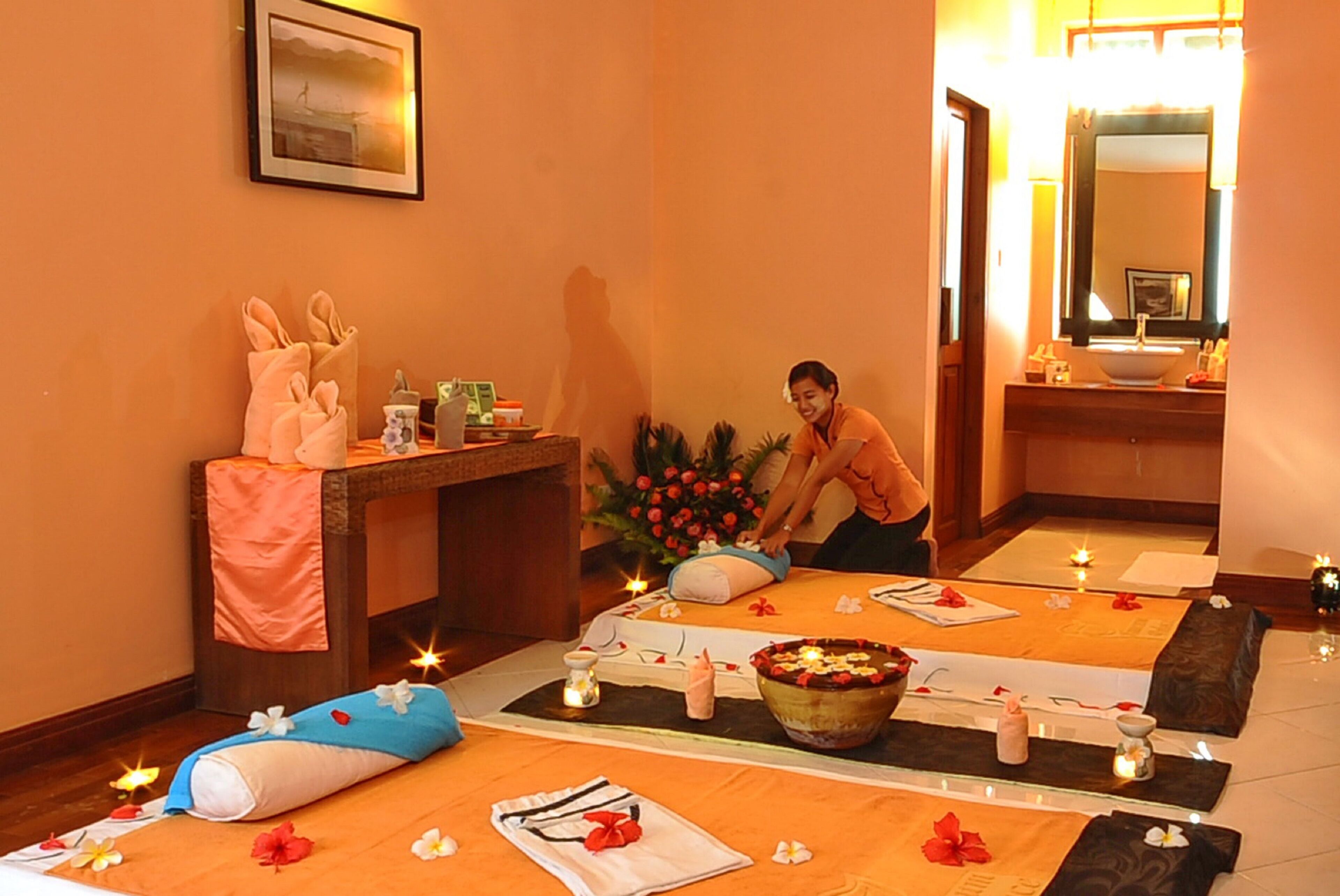 Une salle de spa équipée d’une table de massage, de bougies et d’un panier de fruits.