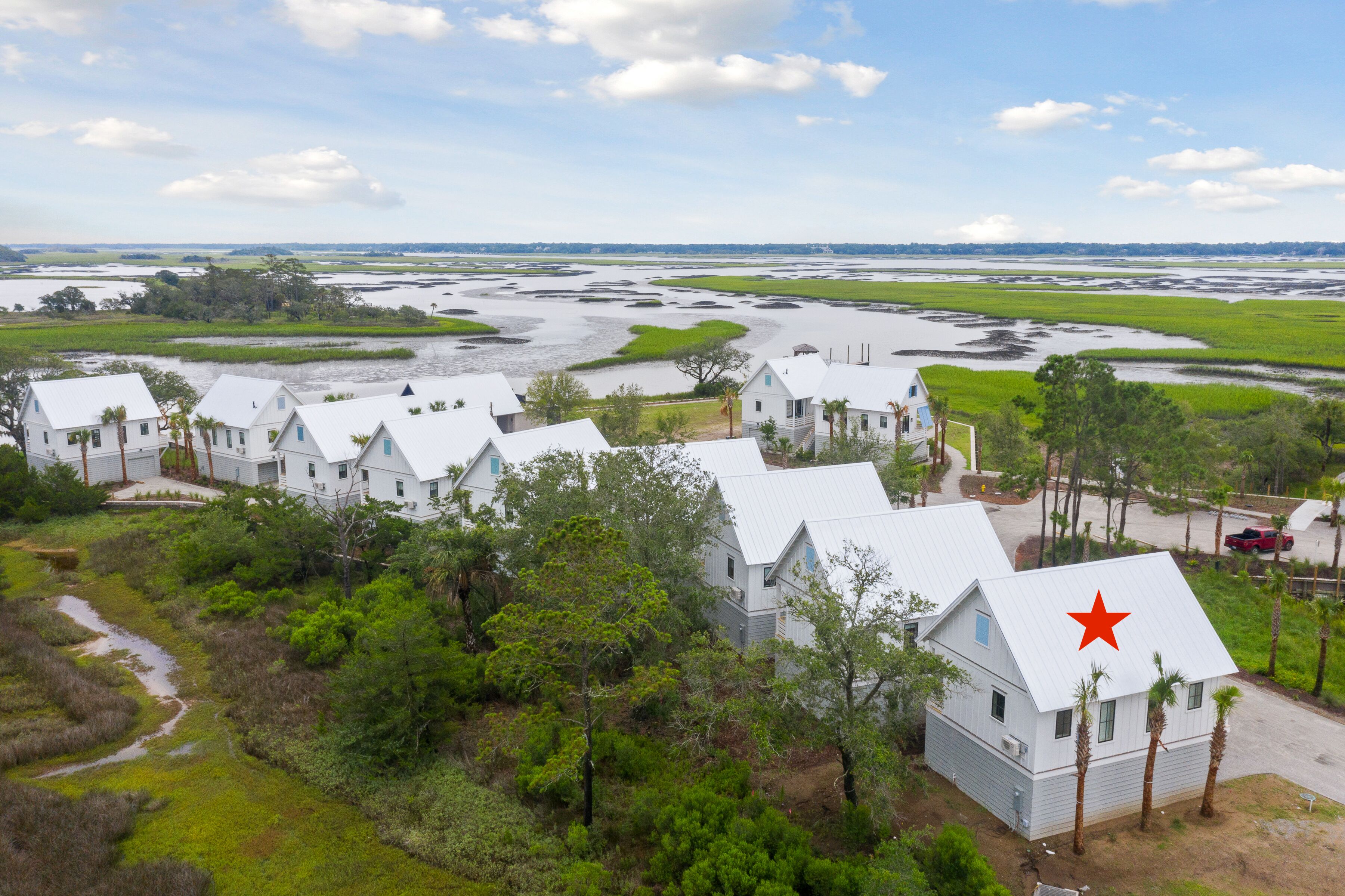 Una propiedad costera con varias edificaciones blancas, una estrella roja en uno de sus techos y un paisaje pantanoso.