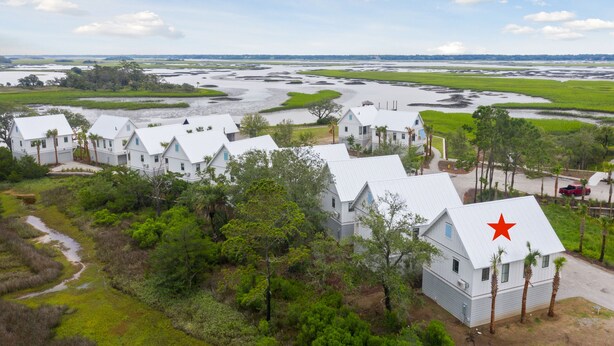 A coastal property with multiple white buildings, a red star on one roof, and a marshy landscape. - "The Goldeneye” (3021 Southerly Way) 2 person creekside bungalow at Kiawah River (Johns Island)