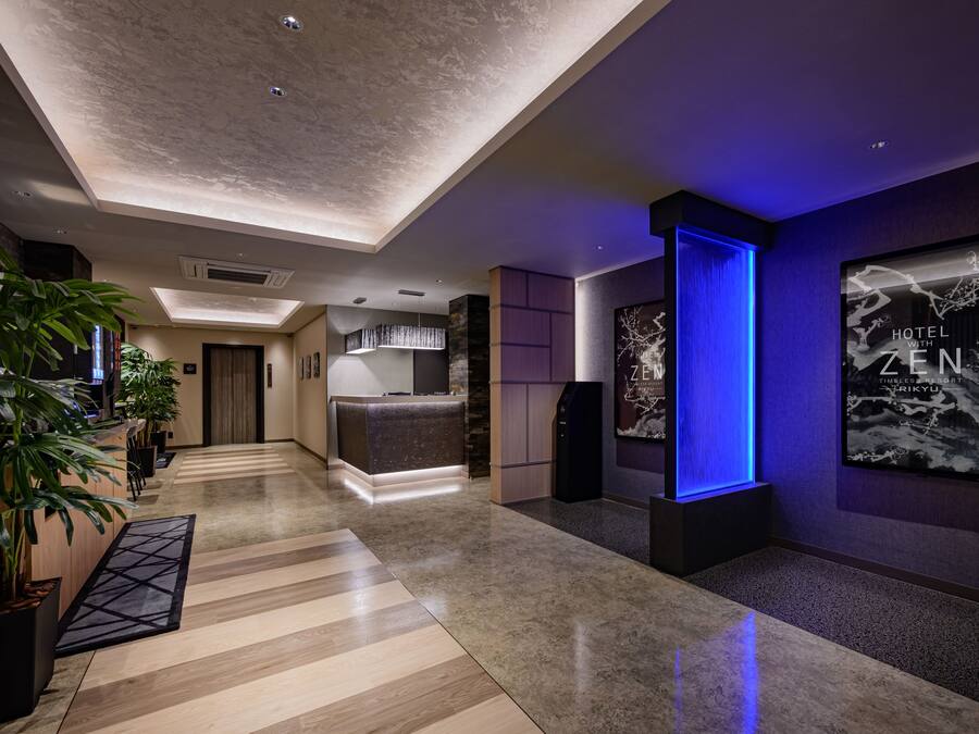 A hotel lobby with a reception desk, a blue accent wall, and a poster advertising the hotel.