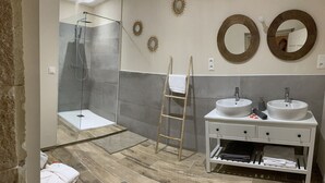 A modern bathroom with a glass-enclosed shower, two sinks, a vanity with storage, and decorative wall mirrors. - Character Suite ⭐️⭐️⭐️ (Milhaud)