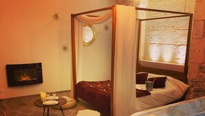 A cozy room with a bed, a hot tub, a fireplace, and a dining area. - Character Suite ⭐️⭐️⭐️ (Milhaud)