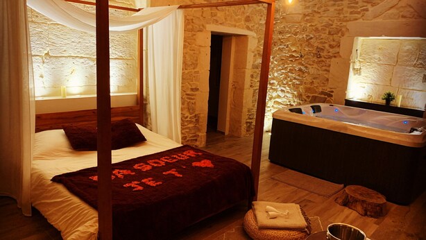A bedroom with a four-poster bed, a stone wall, a bathtub, and a small table with a bucket. - Character Suite ⭐️⭐️⭐️ (Milhaud)