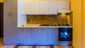 A compact kitchen with a gas stove, sink, and dishwasher. - Residence Hydria (Campofelice di Roccella)