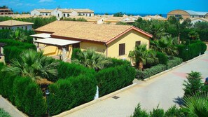 A residential area with a yellow house, palm trees, and a clear sky. - Residence Hydria (Campofelice di Roccella)