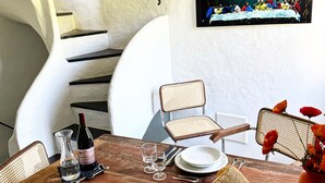 Een eettafel gedekt met borden, glazen, bestek, een fles wijn en een mand met brood.