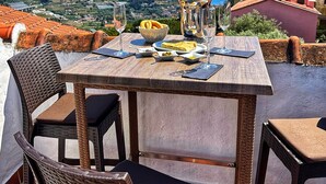 Een terras met een tafel voor twee, uitkijkend over een kustlandschap.