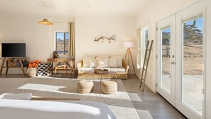Ein geräumiges Zimmer mit einem großen Bett, einer Couch, einem Fernseher und einem Essbereich.