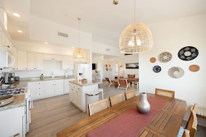 A spacious kitchen with white cabinetry, a central island, and pendant lighting. - Rancho Nopales JT-Pool, Hot Tub, Hammocks & Views (Joshua Tree)