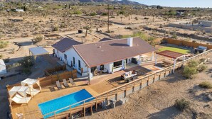 Ein Haus mit Pool, Sitzgelegenheiten im Freien und Blick auf eine Wüstenlandschaft.