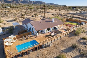 A house with a pool, outdoor seating, and a view of a desert landscape. - Rancho Nopales JT-Pool, Hot Tub, Hammocks & Views (Joshua Tree)