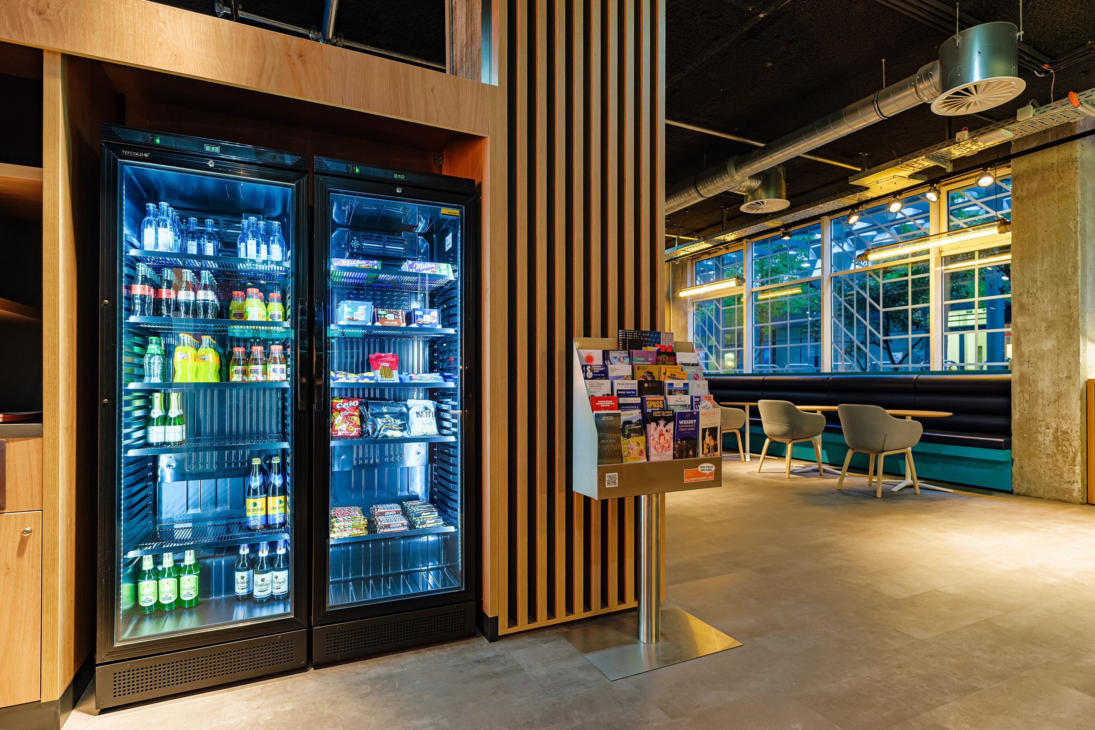 A modern interior with two beverage dispensers, a wooden accent wall, and seating area.