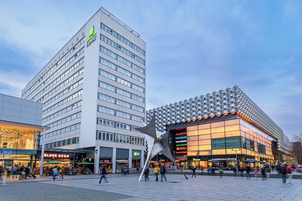 A modern building with a prominent star-shaped structure in front, surrounded by various shops and a hotel. - Holiday Inn Express Dresden Zentrum by IHG (Dresden)