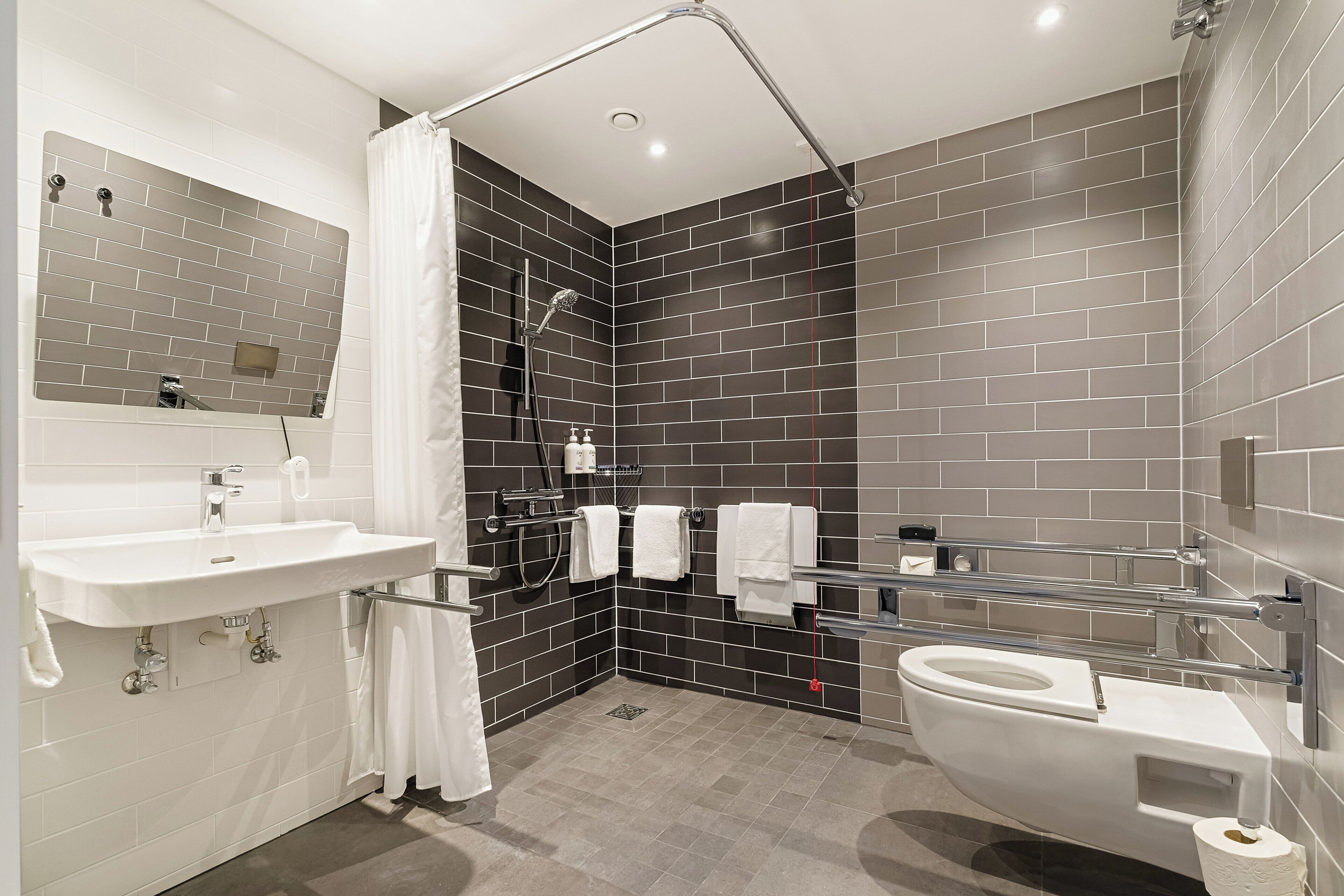 A modern bathroom with a white sink, a toilet, and a shower area.