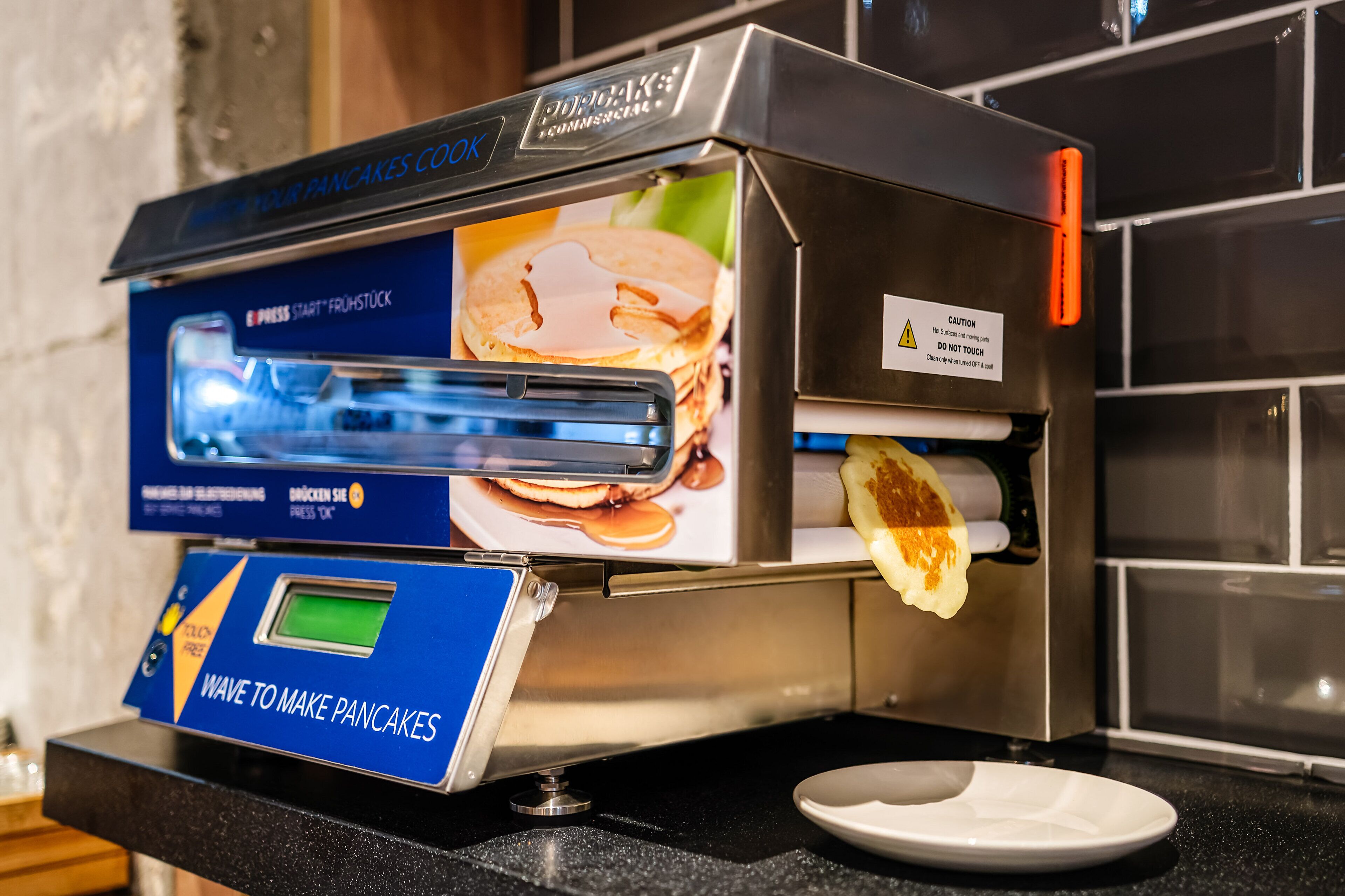 A pancake-making machine with a digital display and a warning label.