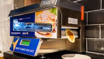 A pancake-making machine with a digital display and a warning label.