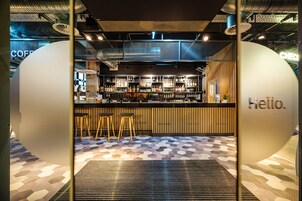 Uma área de bar moderna com banquetas, balcão e um letreiro com a palavra 'Hello'.